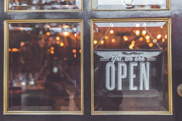 Open vintage sign broad through the glass of store window